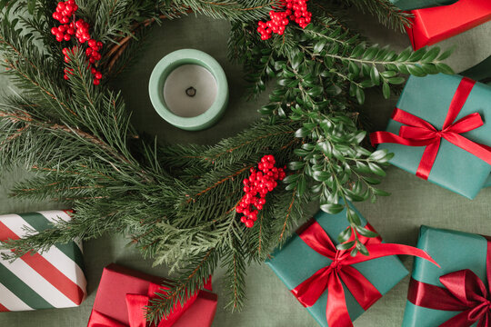 Overhead view of a Christmas wreath with a block candle and assorted wrapped Christmas gifts on a table