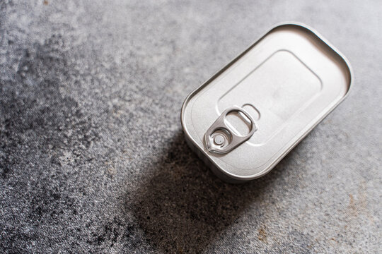 Close-up overhead view of an unopened tin of canned fish on a concrete worktop