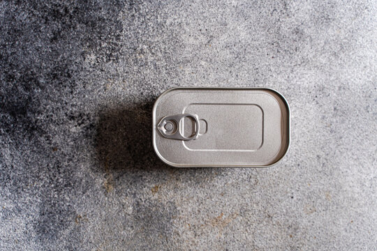 Close-up overhead view of an unopened tin of canned fish on a concrete worktop