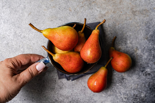 Overhead view of a woman reaching for a cup of fresh pears