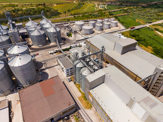 View of a large industrial facility with silos and storage tanks during midday © DSMT