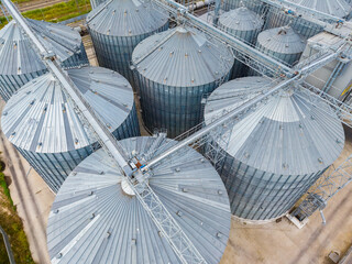 Large grain storage silos in a farm area during daytime showing multiple silos and equipment used for handling crops © DSMT