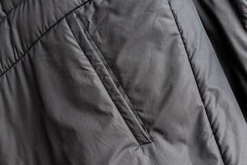 Dark grey puffer jacket pocket texture background with copy space. Winter clothing material surface background with space for text. © ARVD73
