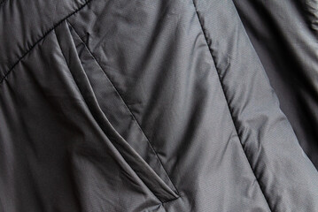 Dark grey puffer jacket pocket texture background with copy space. Winter clothing material surface background with space for text. © ARVD73