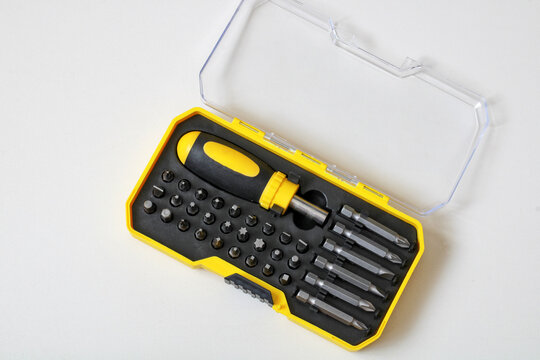 Screwdriver bit set in an open yellow plastic case lies on a white background. Hand tool kit, home repair, and hardware equipment concept for DIY construction projects.