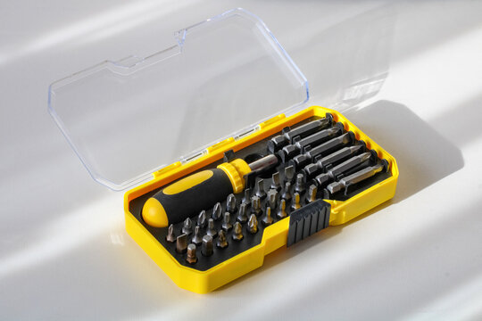Screwdriver bit set stored in a yellow plastic storage case on a light background. Professional hand tool kit for home repair and maintenance projects.