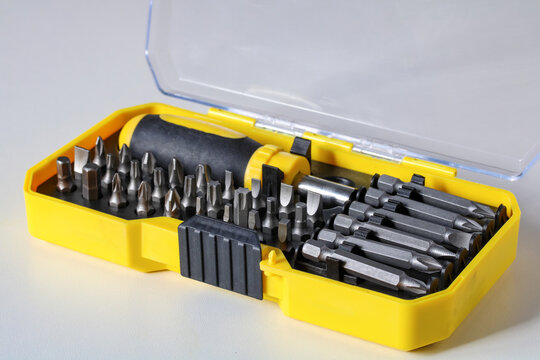 Screwdriver bit set stored in a yellow plastic storage case on a light background. Professional hand tool kit for home repair and maintenance projects.