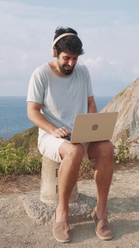 vertical Remote worker video calling on laptop outdoors by the sea