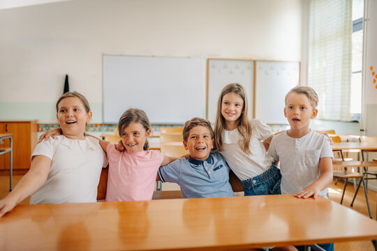 Happy diverse students embracing friendship in classroom