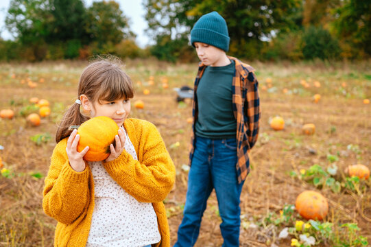 Child girl holding pumpkin with brother in autumn pumpkin patch