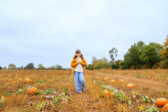 Child girl standing in wide pumpkin patch during autumn harvest