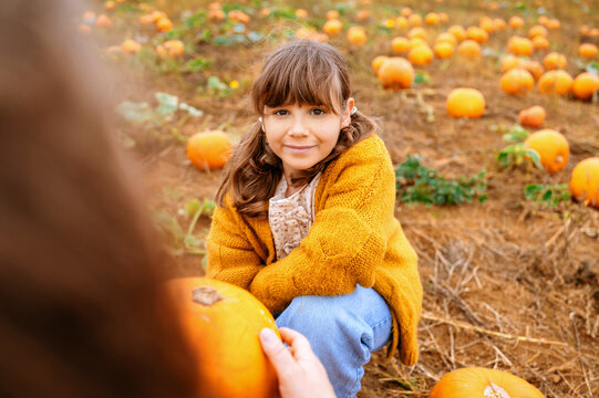 Child girl looking at mother on the pumpkins patch
