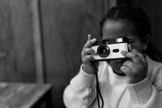 Young mixed race girl taking photos on a disposable film camera