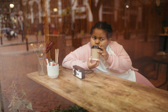 Young girl drinking hot chocolate on an outing to the city