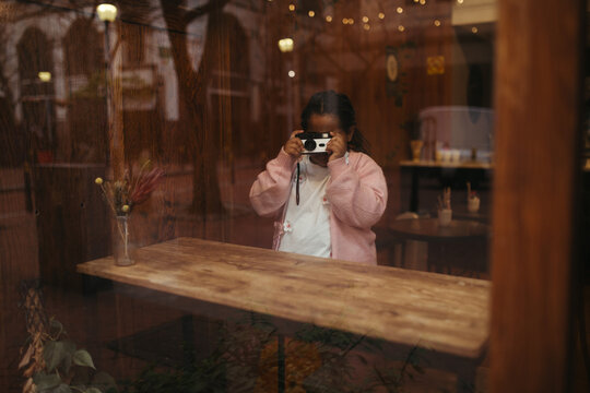 Young mixed race girl taking photos on a disposable film camera