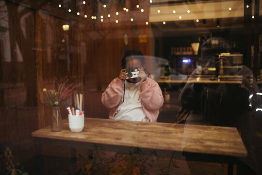 Young mixed race girl taking photos on a disposable film camera