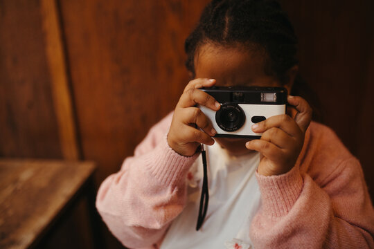 Young mixed race girl taking photos on a disposable film camera