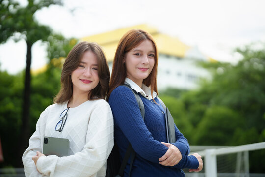 Confident university students stand together on campus with digital tablets, expressing friendship, teamwork, and a positive academic lifestyle in a modern educational setting.