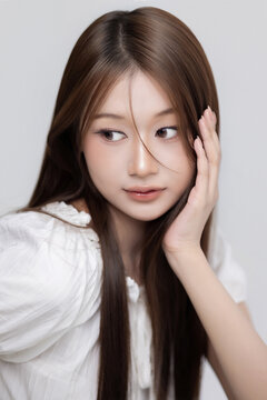 Korean style beauty portrait of lovely young Asian woman with natural glam makeup and sleek brown hair against studio backdrop, Highlighting healthy nails, clear skin, and a Korean beauty aesthetic.