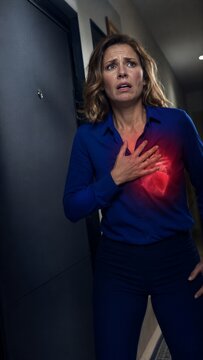 Woman experiencing sudden heart pain clutching chest in agony. Concept of cardiac arrest or cardiovascular health problem. Medical emergency and health distress visualization for assistance.