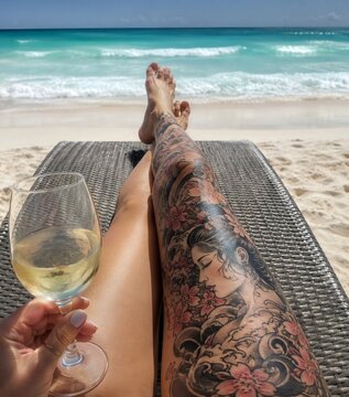Woman enjoying tropical vacation relaxing on beach with white wine