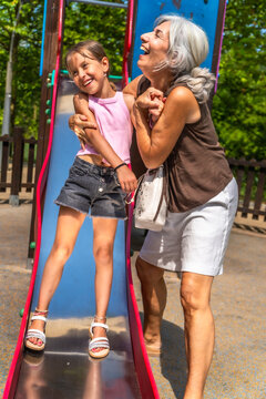 Grandmother and granddaughter enjoying playful moment on slide