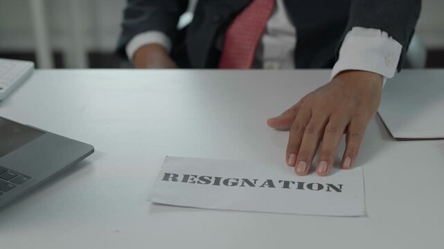 Unhappy businessman pushing resignation letter on desk