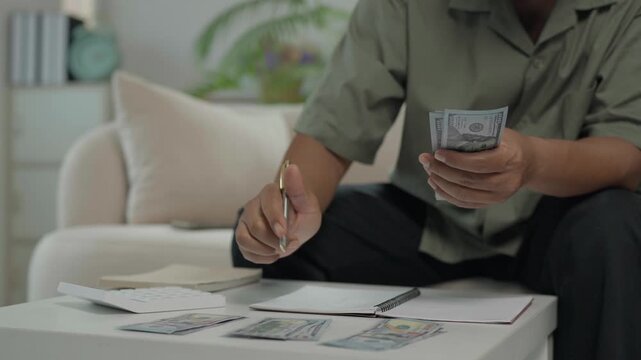 Man counting us dollar bills calculating expenses