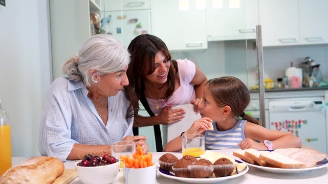 Multigenerational family, including a grandmother, mother, and daughter, enjoying a healthy and joyful breakfast together in a modern kitchen, sharing stories and laughing heartily