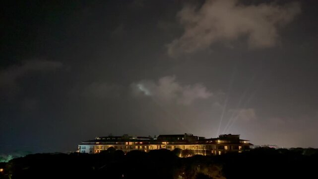 Turkey. 21.07.2026 Resort building illuminated at night with sweeping searchlights in cloudy sky. Luxury hotel exterior view during evening hours. Travel and tourism accommodation.