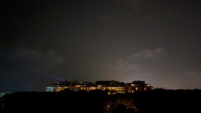 Turkey. 21.07.2026 Hotel building at night with searchlight beam moving across the sky. Dark nocturnal landscape with illuminated resort architecture and bright ray of spotlight.