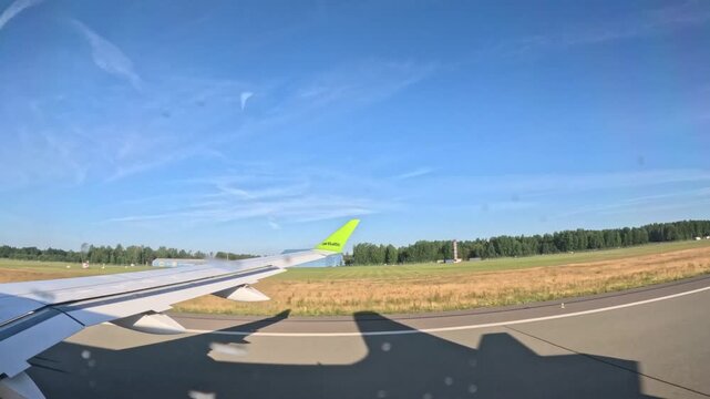 RIGA, LATVIA - JULY 1, 2024: airBaltic airplane taking off from runway and climbing above green landscape