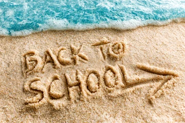 Text Back to school written in the sand of the beach, end of summer vacations message in august or september © Delphotostock