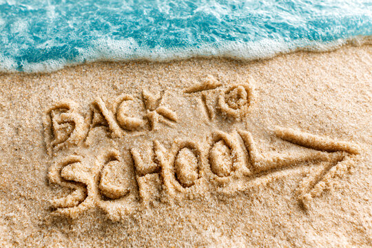 Text Back to school written in the sand of the beach, end of summer vacations message in august or september