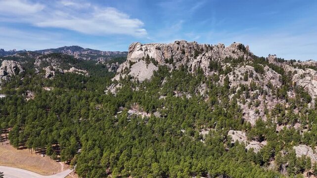 Cinematic drone footage of Mount Rushmore National Memorial in South Dakota, USA, showcasing the monumental granite sculptures of four American presidents surrounded by the scenic Black Hills