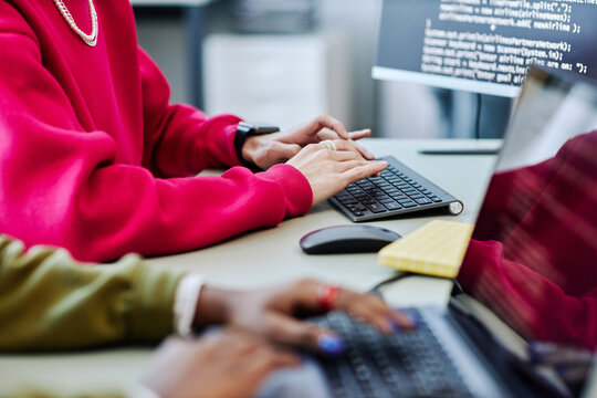 Close up of young person typing at computer keyboard writing code