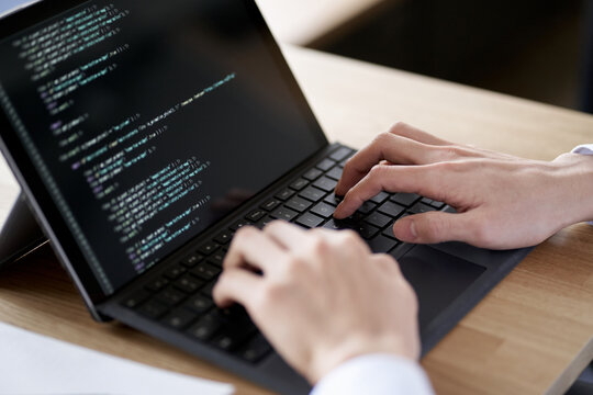 Asian programmer writing code on a laptop