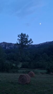 Mountain landscape with a moon and a hay bale in the evening
