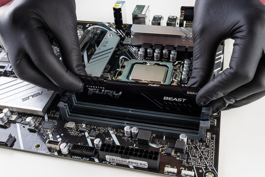 Maykop, Russia - February 18, 2025: The female hands install the kingston fury ddr4 RAM module in the Asus motherboard socket close-up