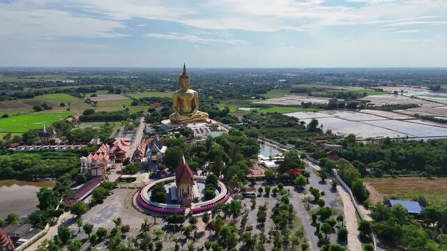 Panoramic aerial orbit of the Golden Buddha and the grand Wat Muang temple in Ang Thong, Thailand. Establishing