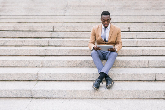 Young businessman sitting on stairs using a tablet