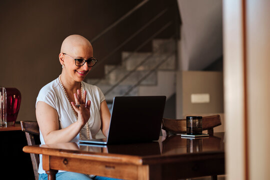 Smiling mature woman waving during video call through laptop at home