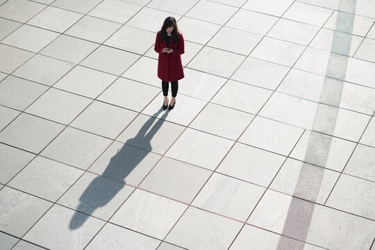 Businesswoman using smartphone and standing on concrete floor