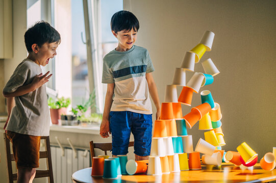 Child watching a colorful paper cup tower fall at home