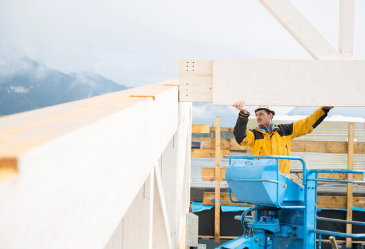 Austria, worker on hoist, positioning roof construction