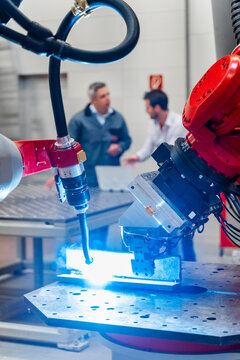 Robotic welding torch welding while male entrepreneurs working in factory