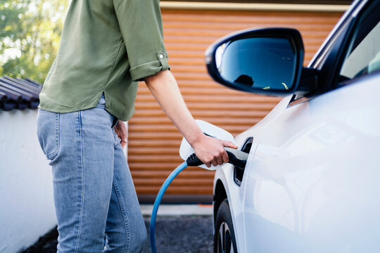Woman wearing jeans charging electric car at station