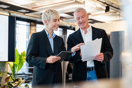 Businessman and businesswoman discuss a document in the office