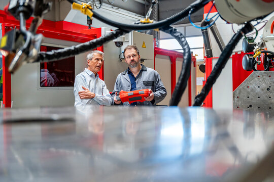 Manager and engineer are inspecting an industrial robot