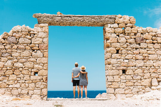 Greece, Milos, Firopotamos Beach, Couple standing in door in stone wall, looking at distance